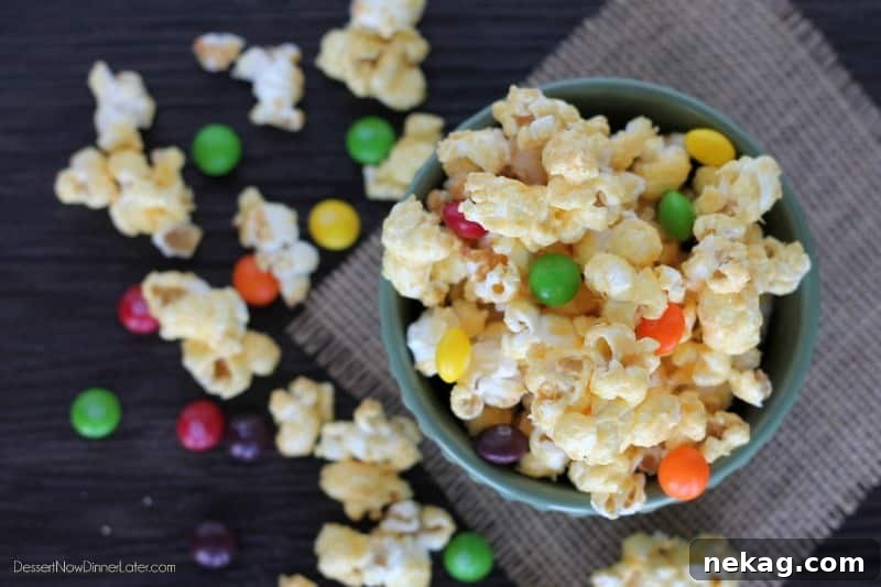 Close-up of golden candied popcorn in a bowl, with colorful Skittles scattered throughout.