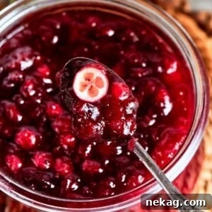 A halved cranberry in sauce showing its tart interior and vibrant red hue, symbolizing fresh flavor and quality.
