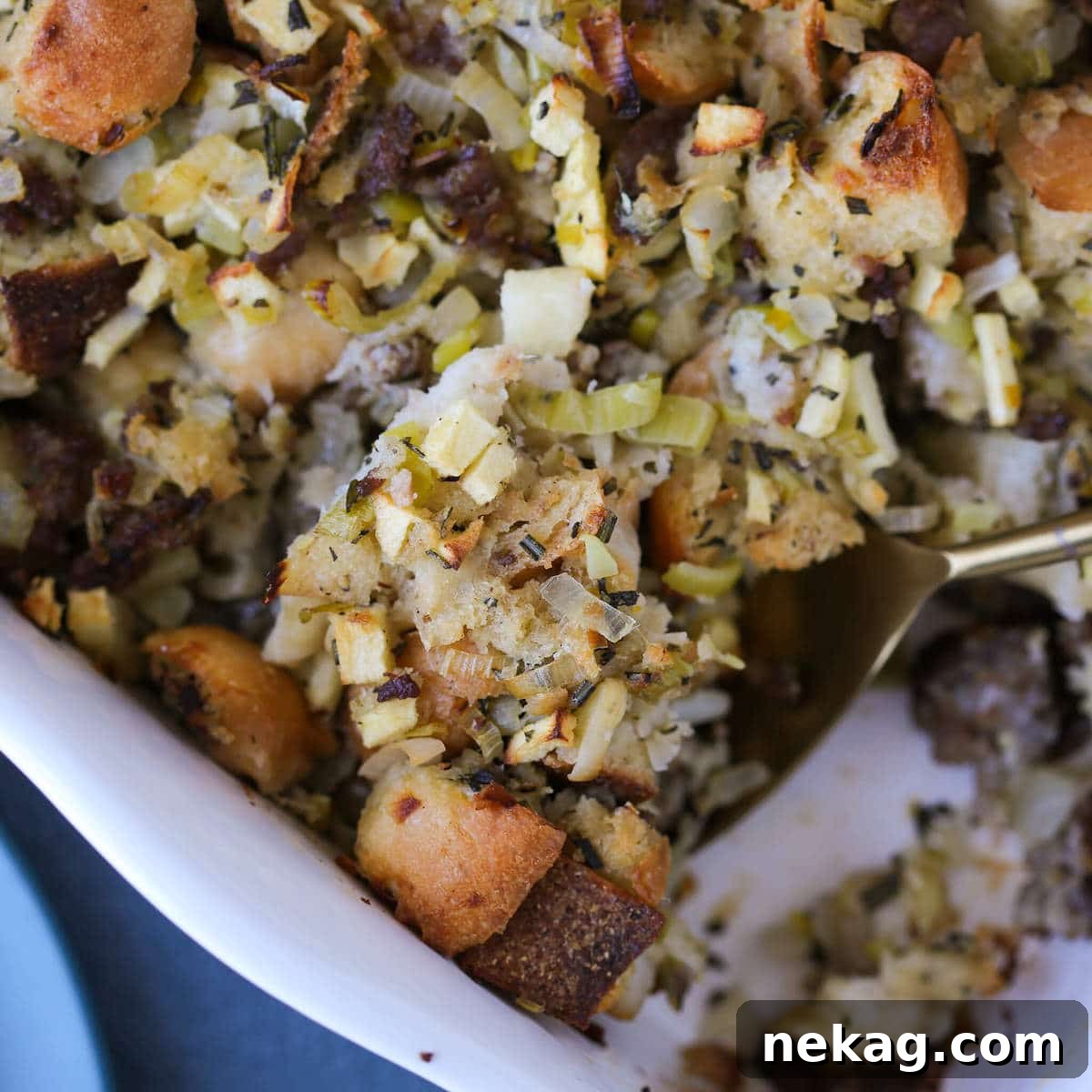 Apple Sage Sausage Stuffing being served with a spoon, showing its moist and flavorful texture.