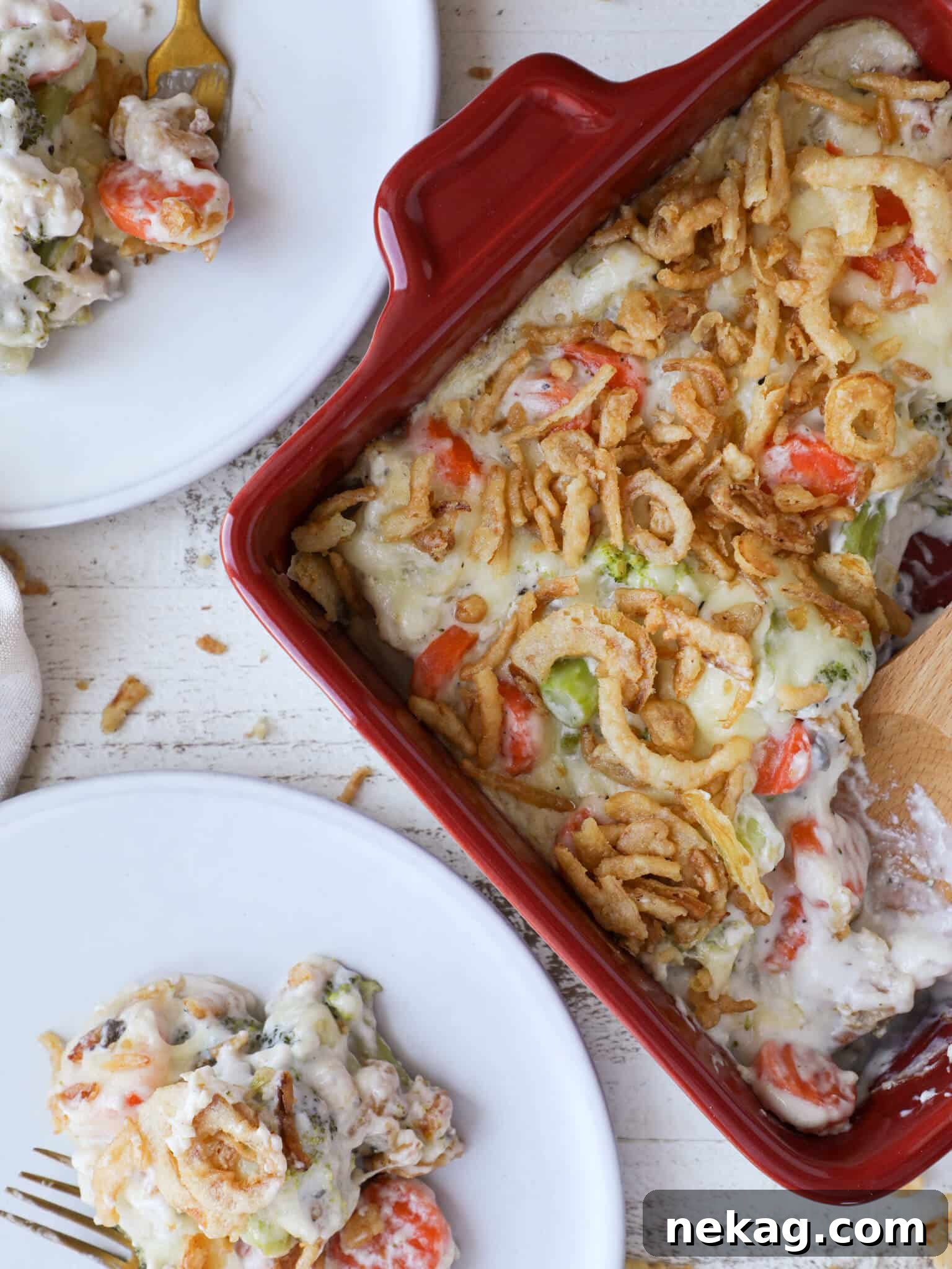 Vegetable casserole served in a red baking dish with two white plates.
