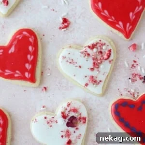 Sweetheart's Delight Cookies 21 An array of beautifully decorated white and red heart-shaped cookies, adorned with pink strawberries and delicate rose petals, creating a romantic display.