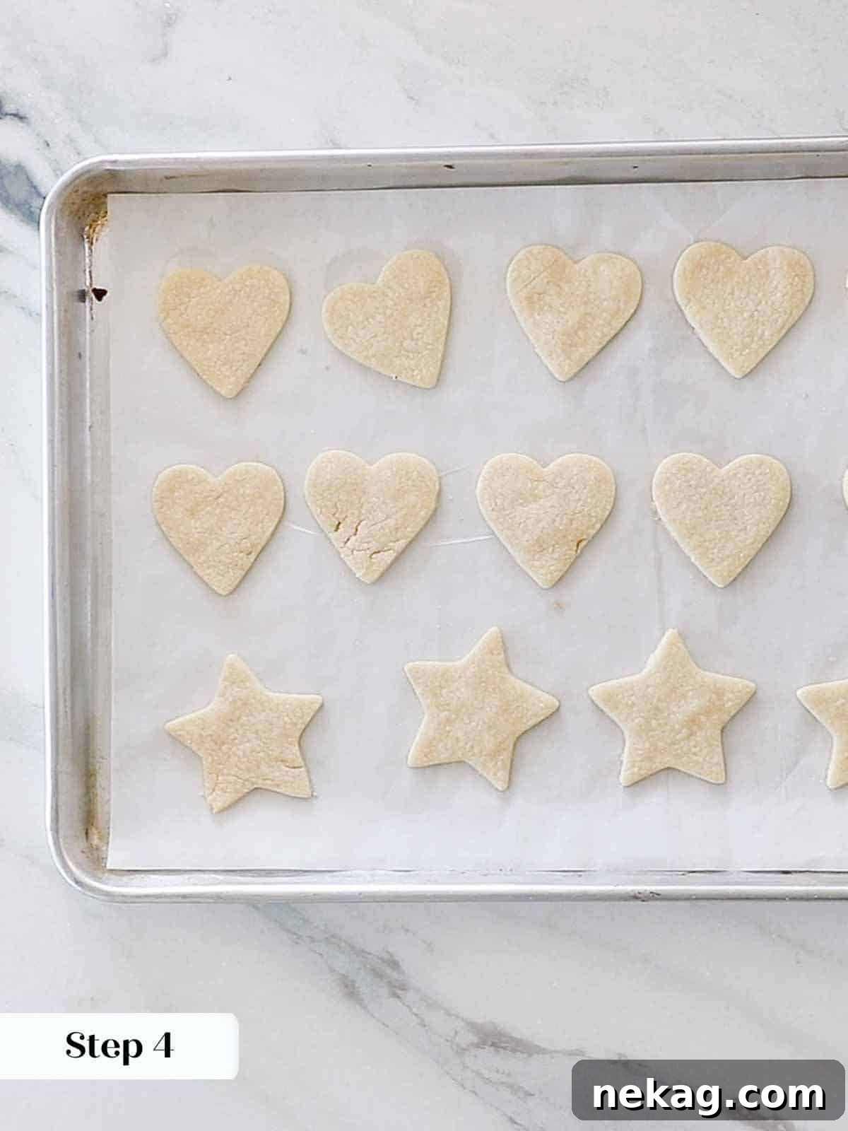 Sweetheart's Delight Cookies 10 Freshly baked heart-shaped sugar cookies cooling on a parchment-lined baking sheet, showing their perfectly held shape and matte finish.