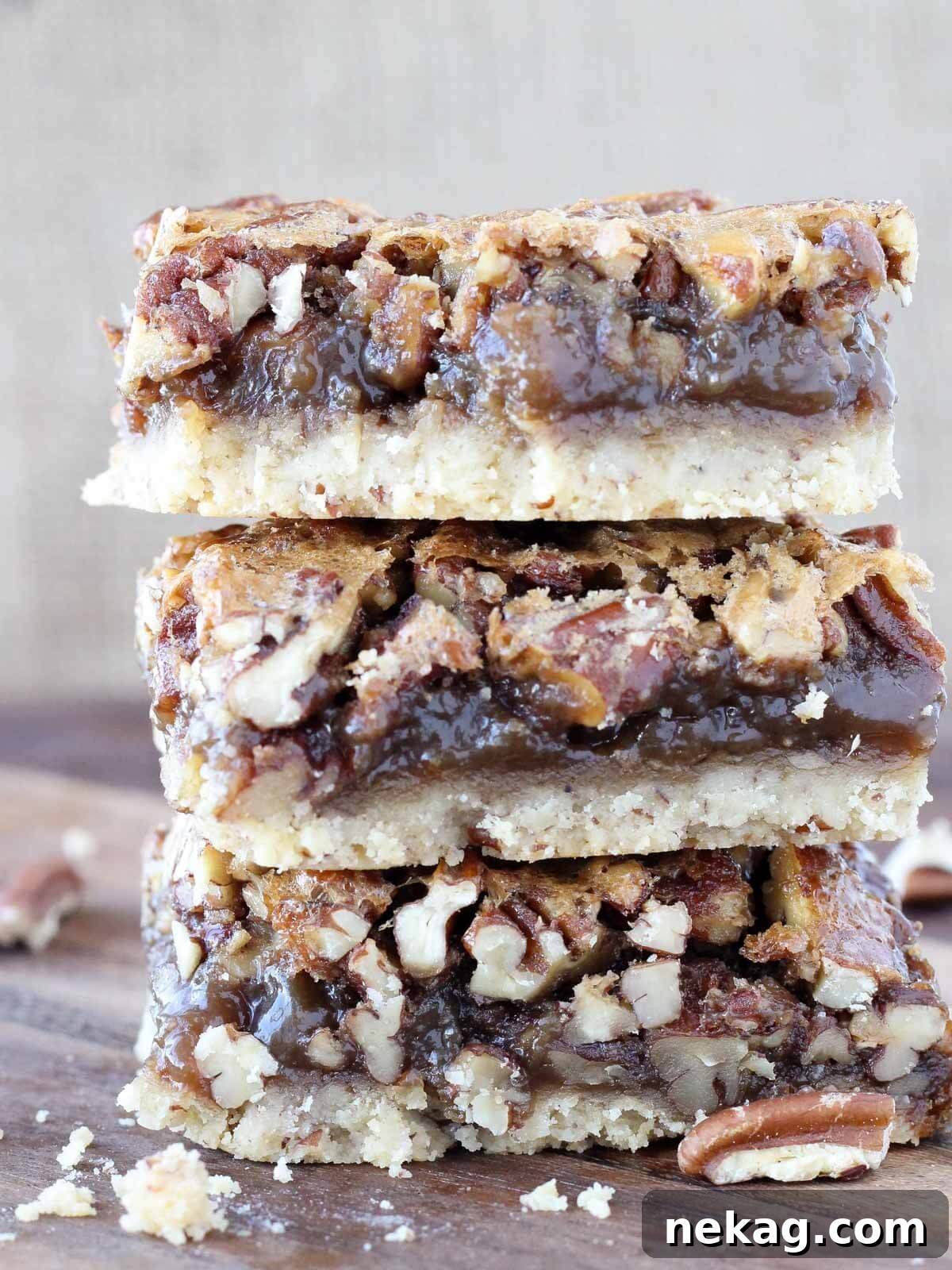 Decadent Pecan Pie Squares 2 Three pecan pie bars stacked, showcasing their layers and delicious texture.