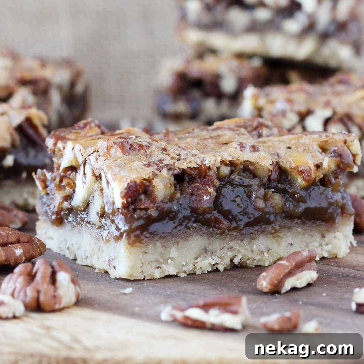 Decadent Pecan Pie Squares 5 pecan pie bar square on a wooden board, highlighting its perfect shape and texture.
