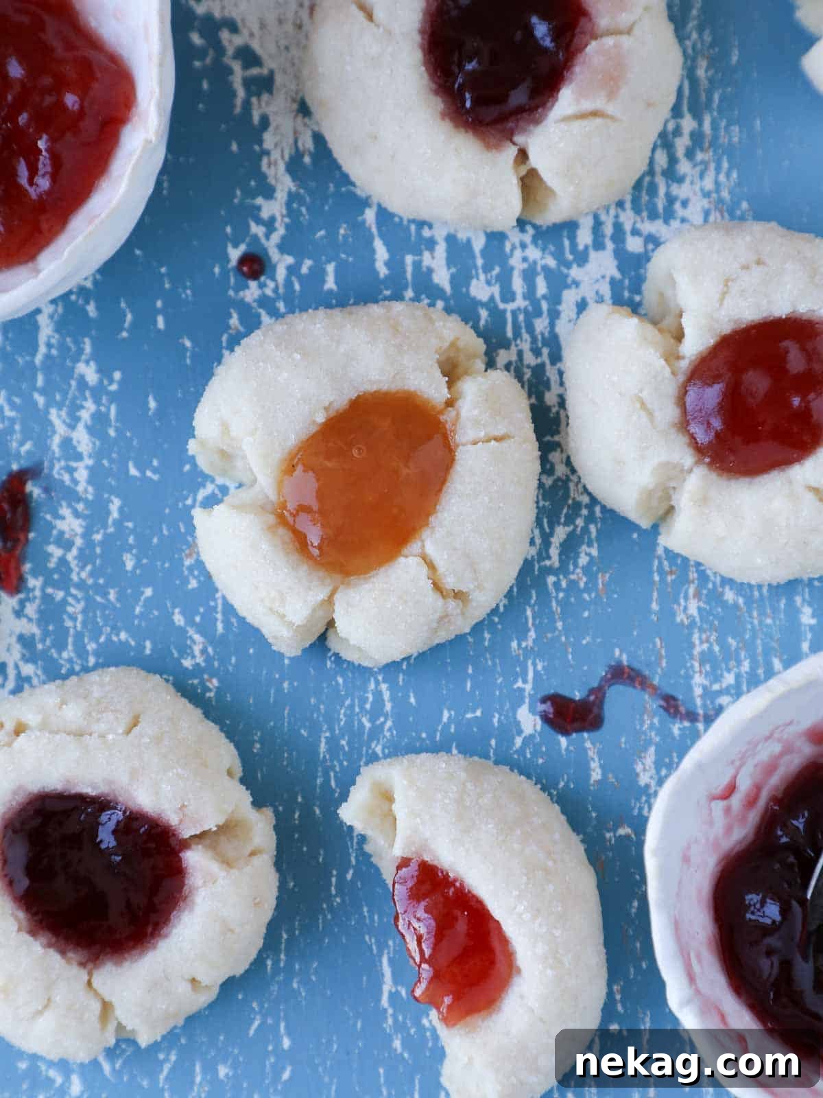 Preserve-Kissed Shortbreads 2 A beautiful spread of thumbprint cookies on a blue board, showcasing various jam fillings.