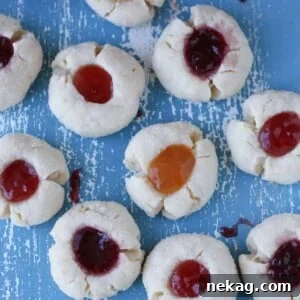 A collection of thumbprint cookies with various jam fillings scattered artfully.