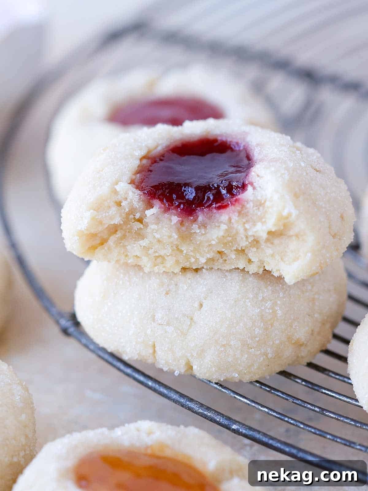 Preserve-Kissed Shortbreads 3 A thumbprint cookie broken open on a wire rack, revealing its soft, tender interior and jam filling.