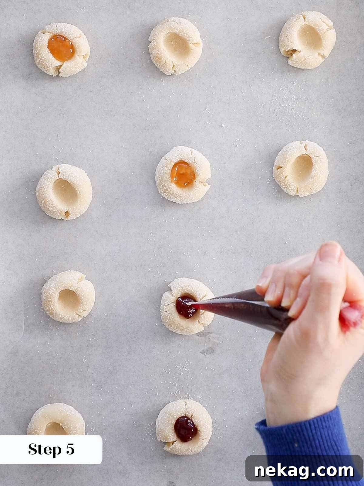 Preserve-Kissed Shortbreads 9 Spoon filling thumbprint cookies with jam before they are baked.