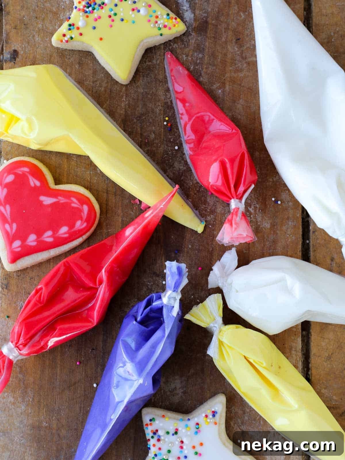 Flawless Royal Icing Made Easy with Meringue Powder 3 red purple yellow and white bags of royal icing.