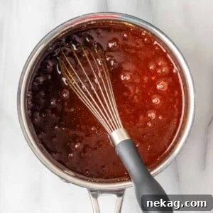 Homemade BBQ sauce boiling gently, showing its rich texture.