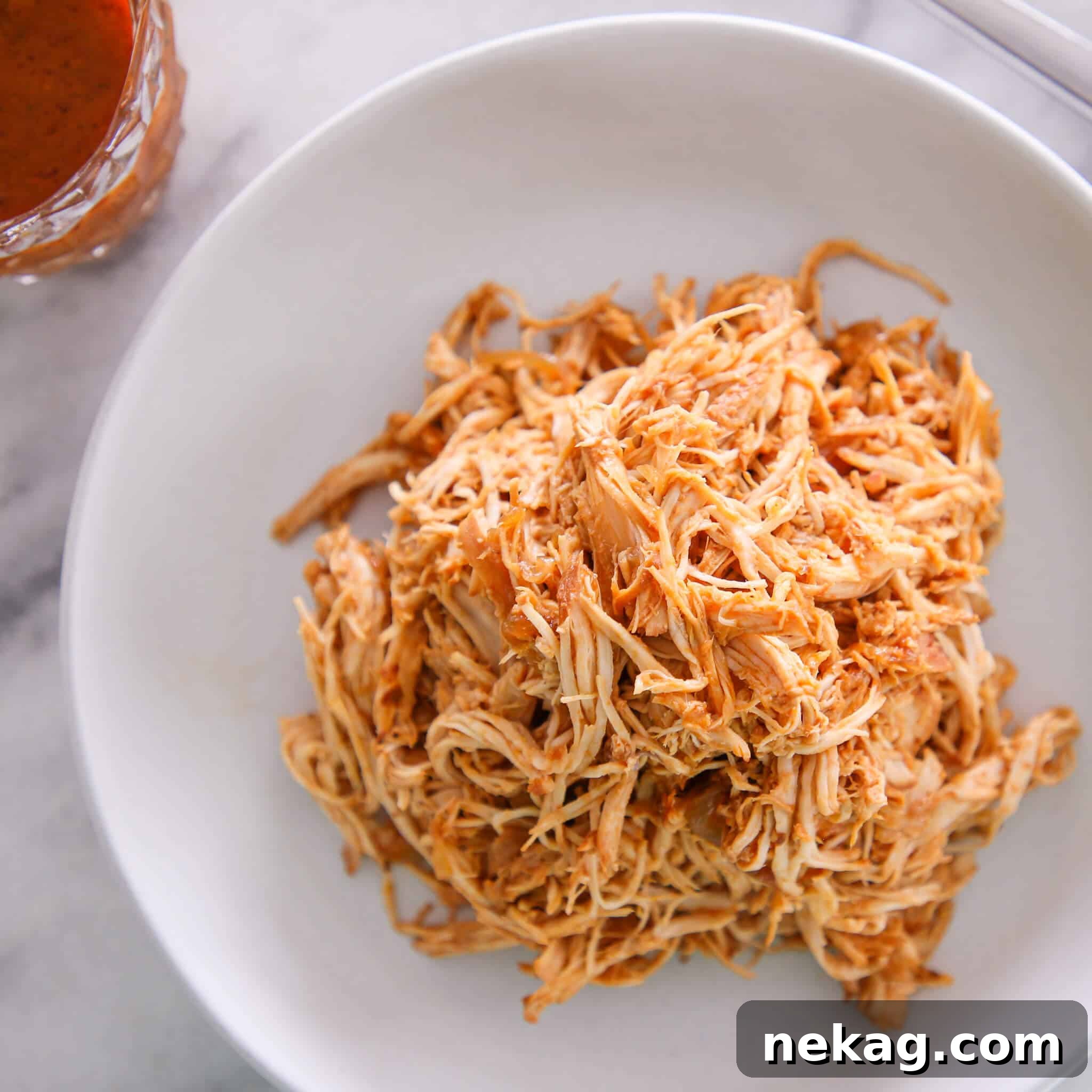 Hearty slow cooker barbecue pulled chicken served in a white bowl.