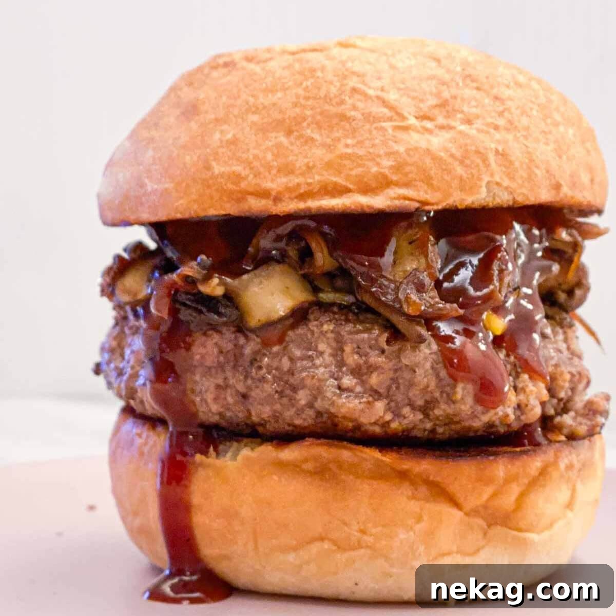 A gourmet burger with homemade BBQ sauce generously dripping down.