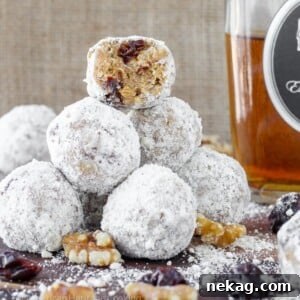 A close-up shot of several No-Bake Gingersnap Brandy Balls coated in powdered sugar, arranged on a festive plate.