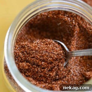 Homemade taco seasoning in a jar on a yellow plate with a tiny spoon, ready for use.