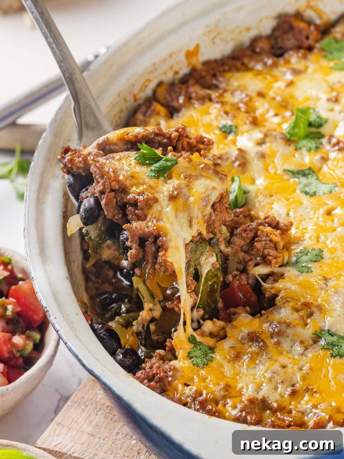 Delicious taco bake being served with a satisfying cheese pull, highlighting the rich, melted cheese and vibrant layers.