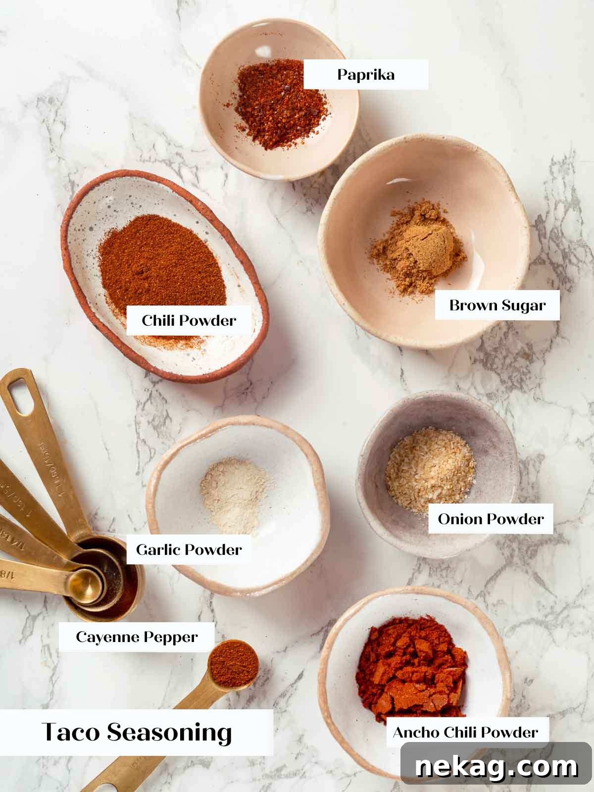 Bowls of various taco seasoning ingredients laid out on a marble surface, ready for mixing.