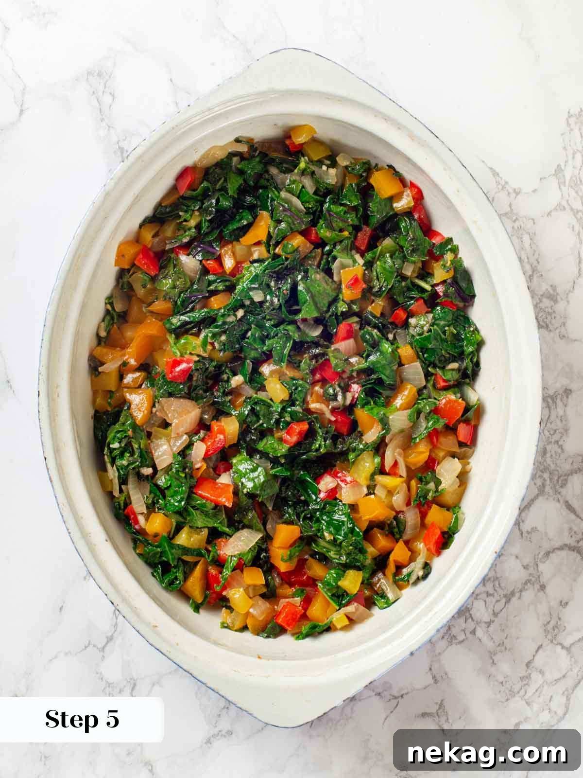 Adding the cooked bell peppers, onions, and kale mixture to the bottom of a casserole dish.