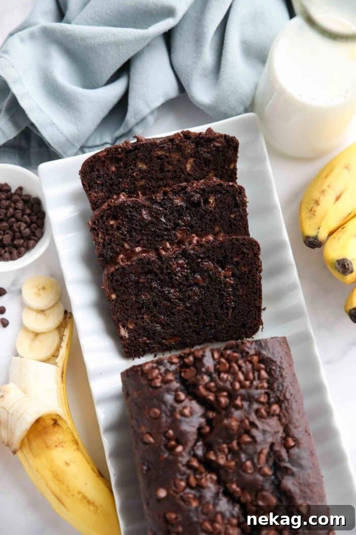 Top view of a freshly baked loaf of chocolate banana bread on a serving plate with a few slices already cut, revealing its moist interior and chocolate chips.