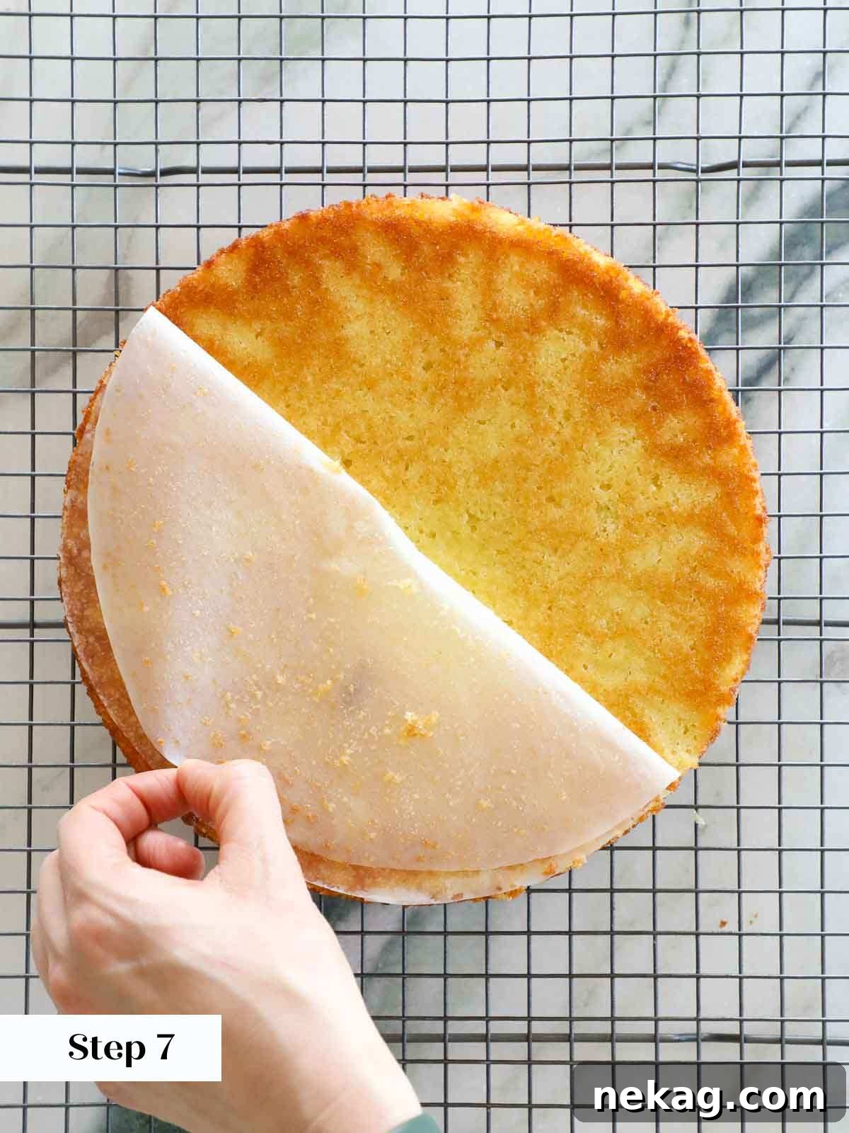 Sun-Kissed Lemon Olive Oil Cake 11 pealing parchment circle from bottom of cooling cake.