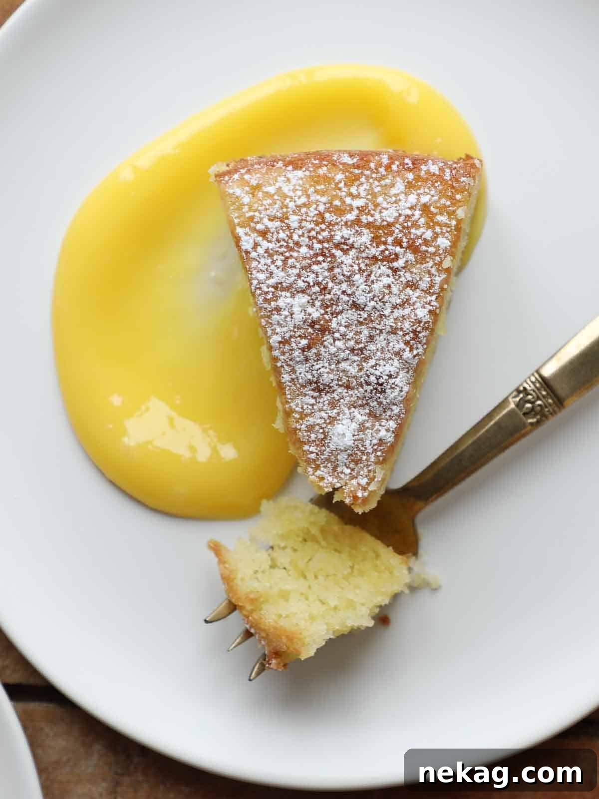 Sun-Kissed Lemon Olive Oil Cake 12 powdered sugar on slice of olive oil cake on white plate with lemon curd.