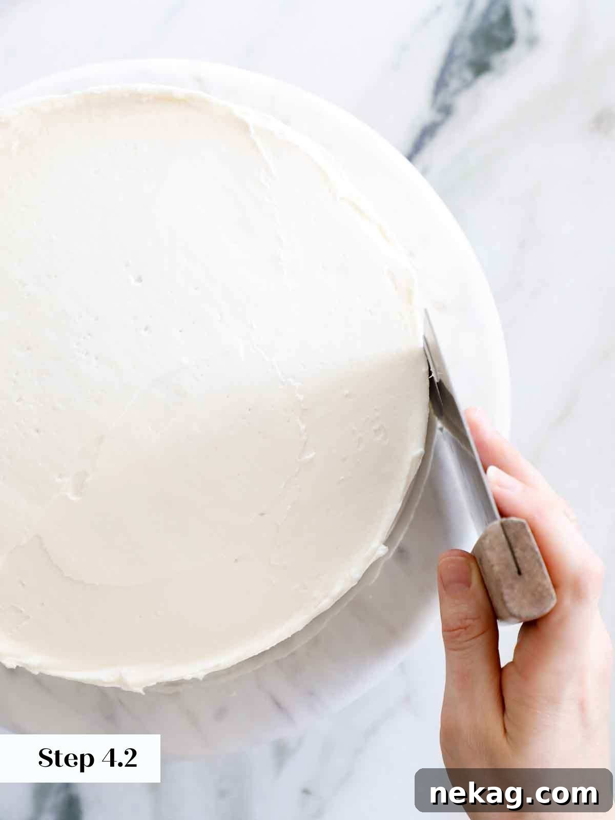 Perfectly Moist Vanilla Cake 24 smoothing sides of cake with bench scraper.