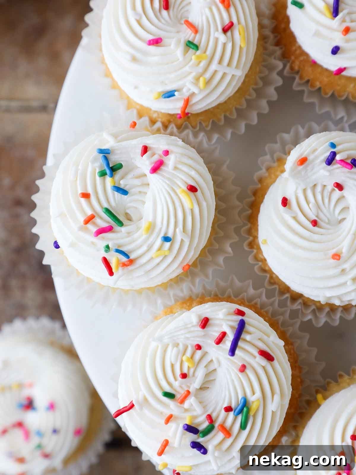 Fluffy Vanilla Delights 3 Piped frosting with colorful sprinkles on top of vanilla cupcakes.