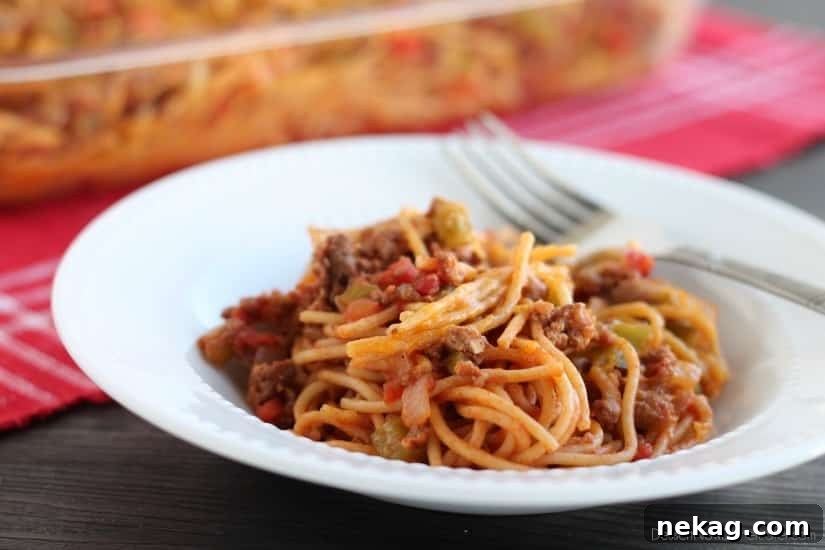 A dish of freshly baked Confetti Spaghetti topped with melted cheddar cheese.