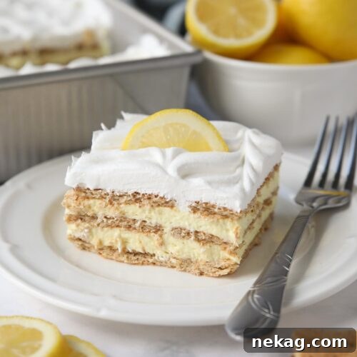 A slice of lemon icebox cake, beautifully layered with graham crackers, lemon pudding, and whipped topping, on a white plate with a fork.