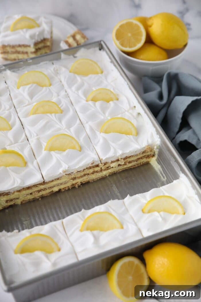 A 9x13-inch baking pan filled with the layered lemon icebox cake, topped with whipped cream and lemon slices, ready for serving after chilling.