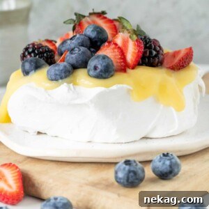 A beautifully arranged pavlova topped with vibrant lemon and fresh fruit, set on a rustic wooden slate.