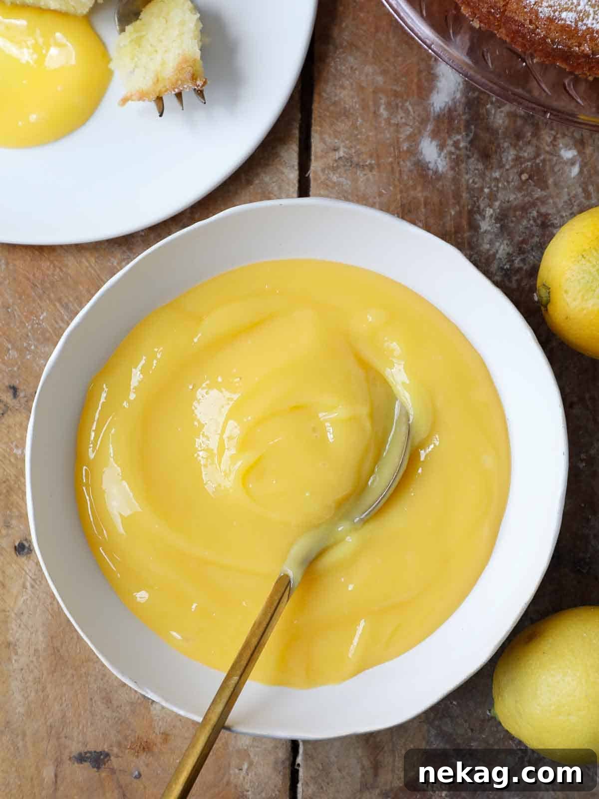 A pristine white bowl holds a generous portion of smooth, creamy lemon curd, ready for use in baking.