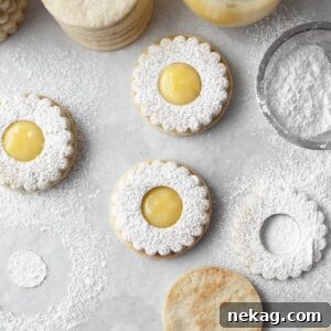 A cluster of beautifully decorated Lemon Linzer Cookies, dusted with powdered sugar and filled with bright lemon curd.