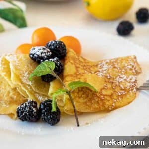Beautifully folded Lemon Curd Crepes, artfully arranged and topped with fresh blackberries.