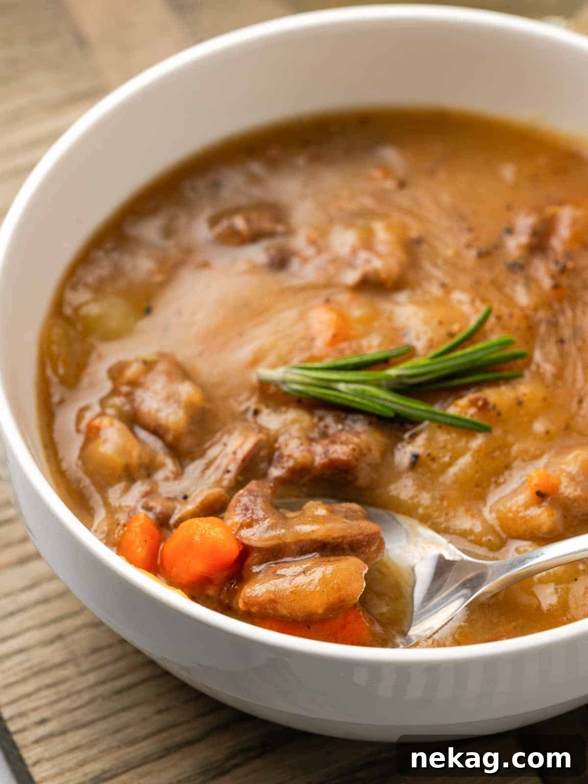 Hearty Lamb Stew 2 A hearty lamb stew on a spoon, garnished with a fresh rosemary sprig, ready to be served.