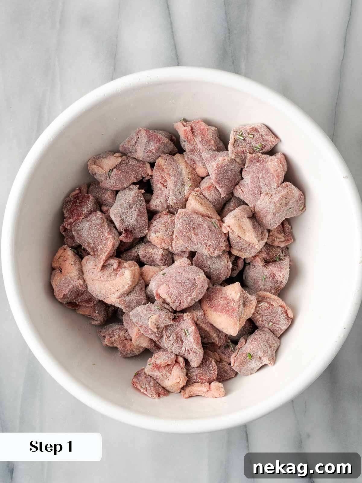 Hearty Lamb Stew 6 Cubed lamb coated evenly with flour and herbs in a mixing bowl, ready for browning.