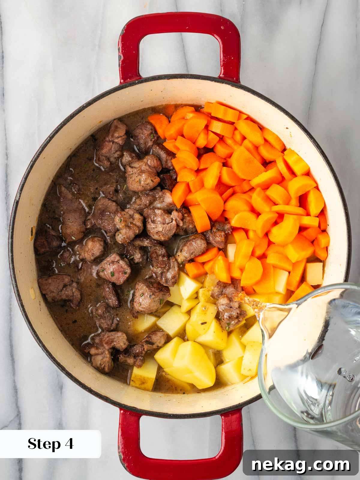 Hearty Lamb Stew 9 Water being added to a Dutch oven filled with browned lamb, onions, carrots, and potatoes, ready for simmering.