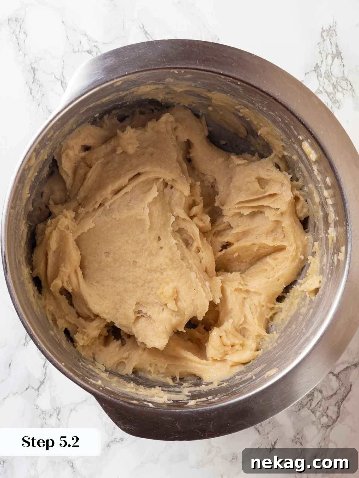 Rippled Golden Doughnuts 12 A mixing bowl filled with fully mixed, sticky cruller dough, showcasing its cohesive and pliable texture, ready for piping.