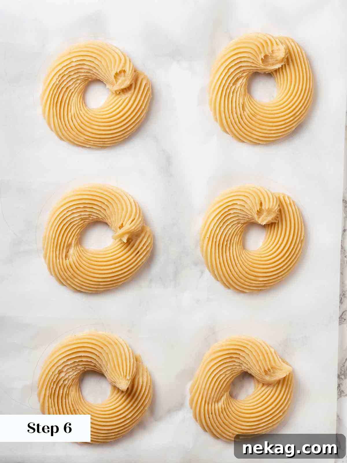 Rippled Golden Doughnuts 13 Cruller dough expertly piped into intricate, ridged rings on parchment paper, awaiting the chilling and freezing process.