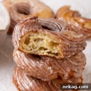 A French cruller with a bite taken out, showing the airy internal structure and golden crust, signifying its deliciousness.