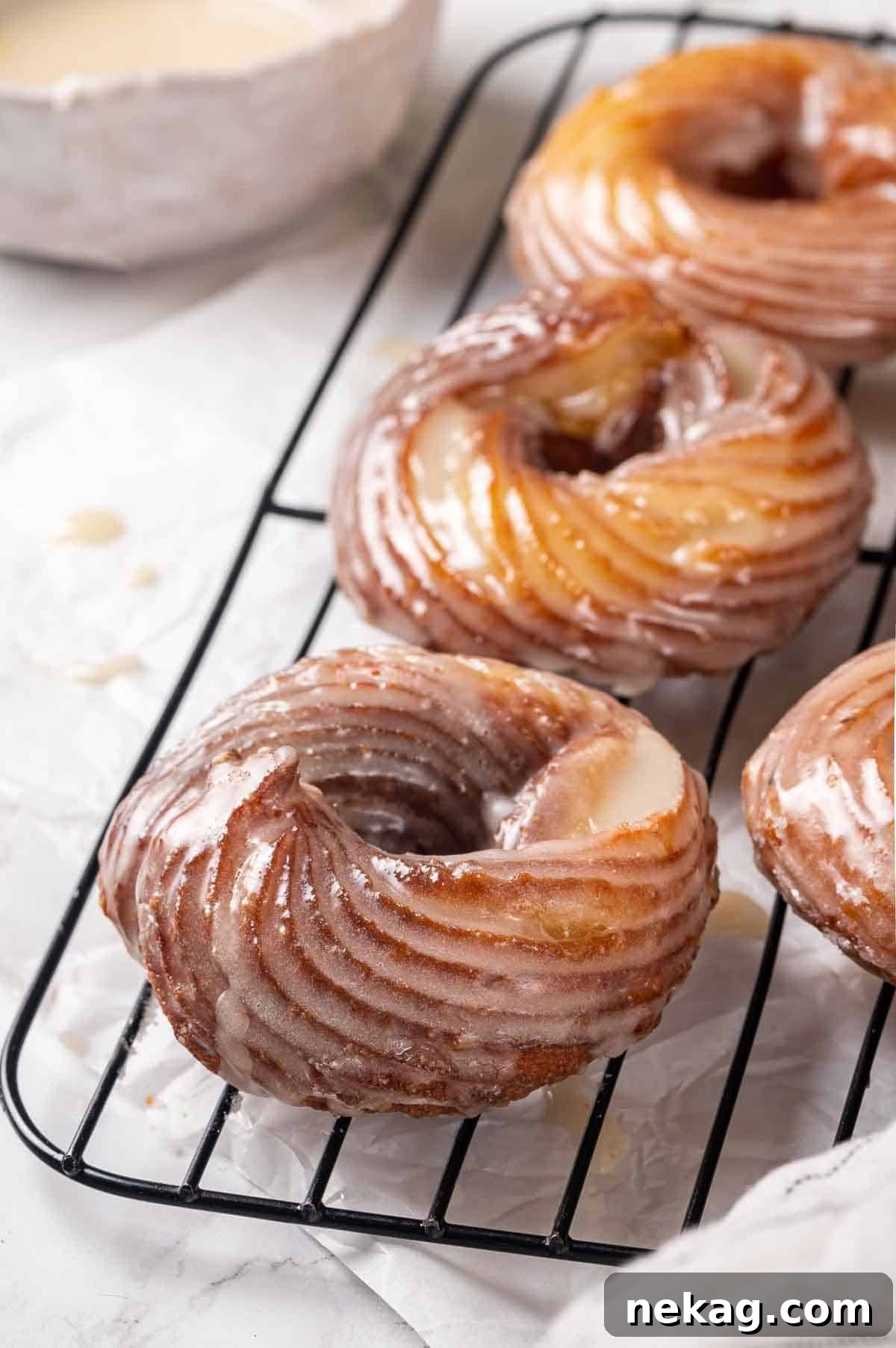 Rippled Golden Doughnuts 6 Freshly fried, golden French crullers cooling on a wire rack, glistening and ready for their maple glaze.