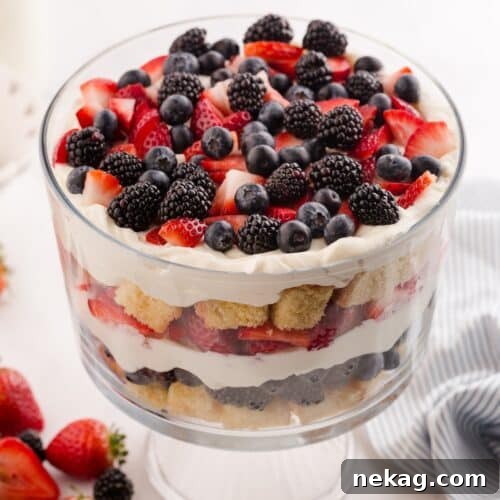 Red white and blue trifle in a clear trifle bowl showing layers of pound cake, whipped cream cheese, and berries.