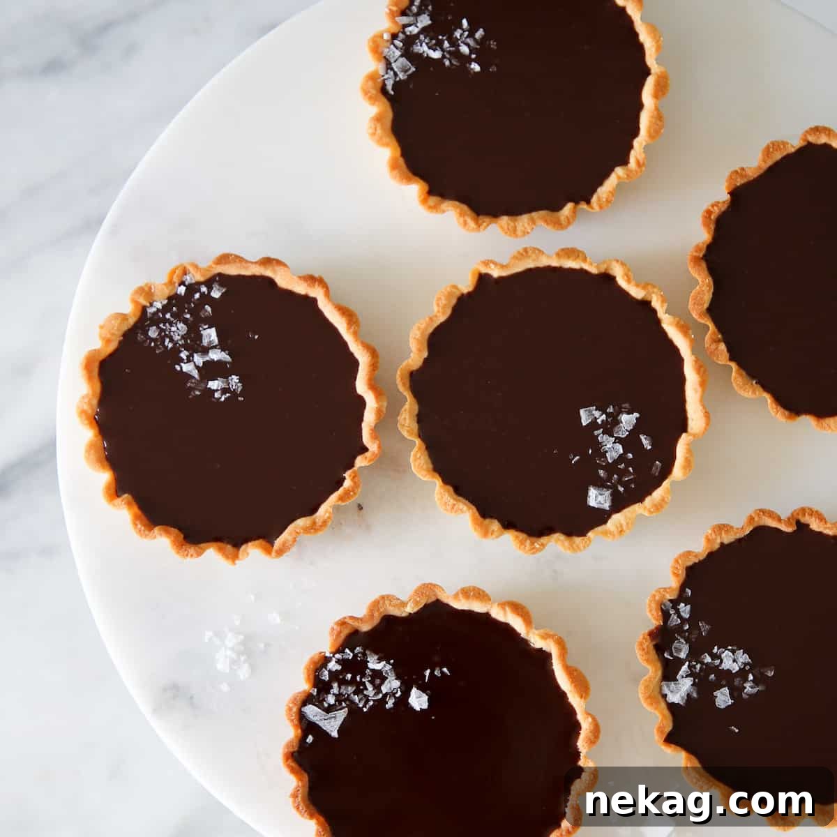 Mastering Chocolate Ganache 5 mini salted chocolate tarts on marble cake stand