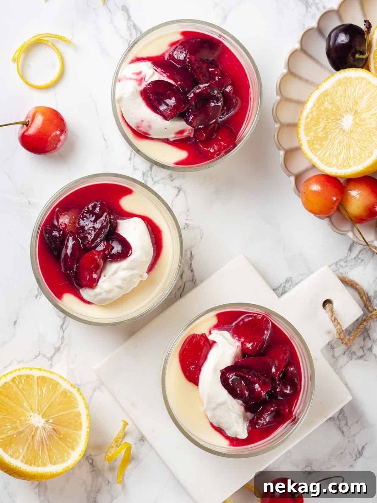 Velvet Lemon Delight 11 Three beautifully arranged lemon possets in glasses, generously garnished with swirls of whipped cream and a rich homemade cherry sauce, ready for serving.