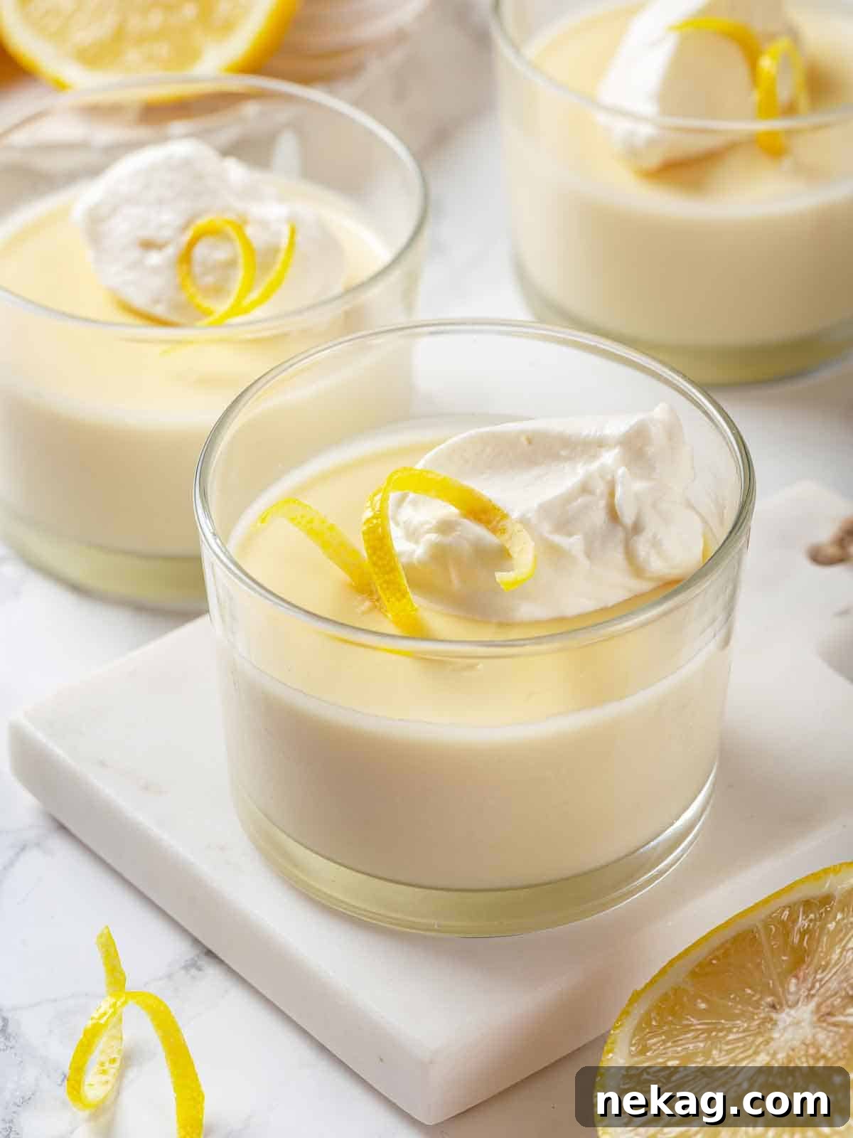 Velvet Lemon Delight 12 Three elegant glasses of lemon posset, topped with artistic swirls of homemade whipped cream, presented beautifully for serving.