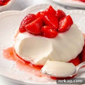Buttermilk panna cotta with strawberries and a bite taken on a spoon.