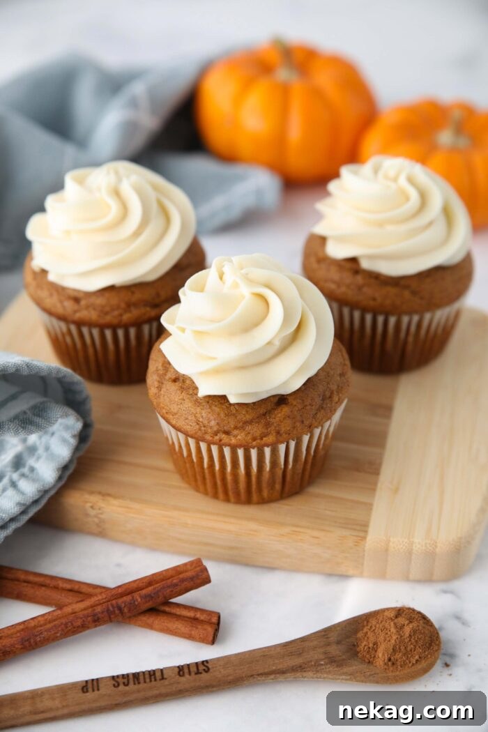 Harvest Pumpkin Spice Cupcakes 2 Beautifully piped pumpkin cupcakes with creamy cream cheese frosting on a rustic cutting board, capturing the essence of fall baking.