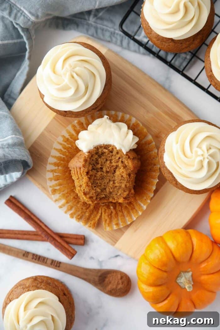 Harvest Pumpkin Spice Cupcakes 11 A delicious pumpkin cupcake with a bite taken out, revealing the moist cake and rich cream cheese frosting.
