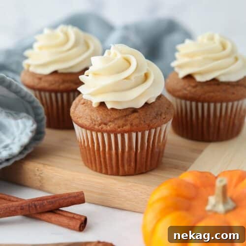 Side view of pumpkin cupcakes with cream cheese frosting piped on top, ready to eat.