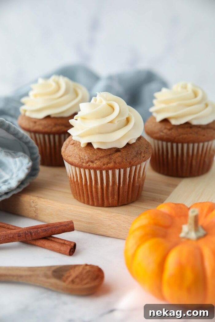 Harvest Pumpkin Spice Cupcakes 3 A close-up side view of a perfectly frosted pumpkin cupcake, showcasing the light cake and abundant cream cheese swirls.