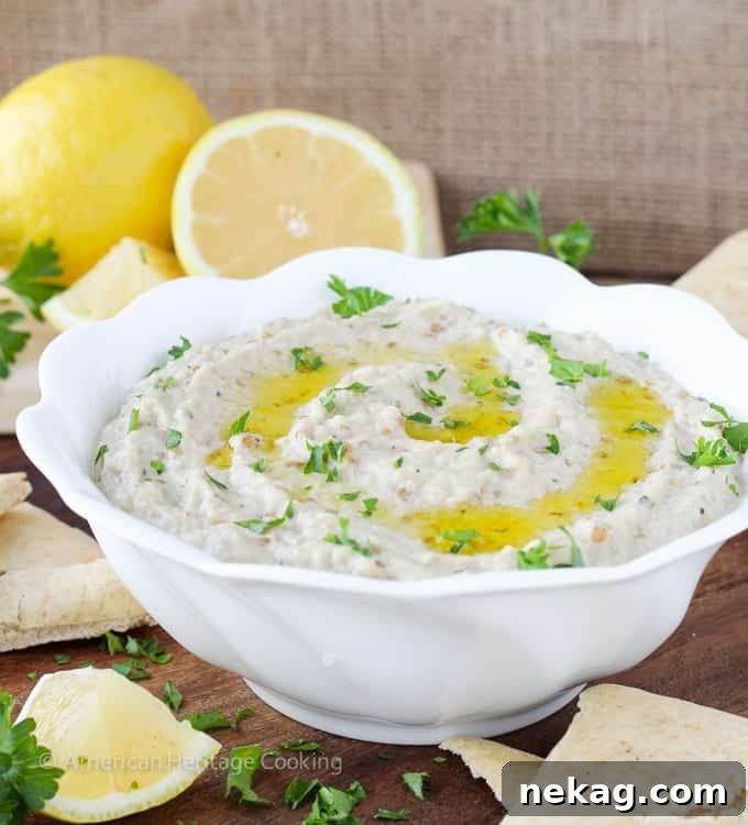 Velvety Smoked Eggplant Dip 6 A vibrant platter featuring a bowl of Baba Ganoush, surrounded by fresh pita bread triangles and colorful vegetable sticks, perfect for a gathering.